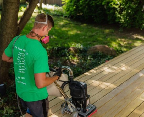 Sanding a deck surface in preparation for staining