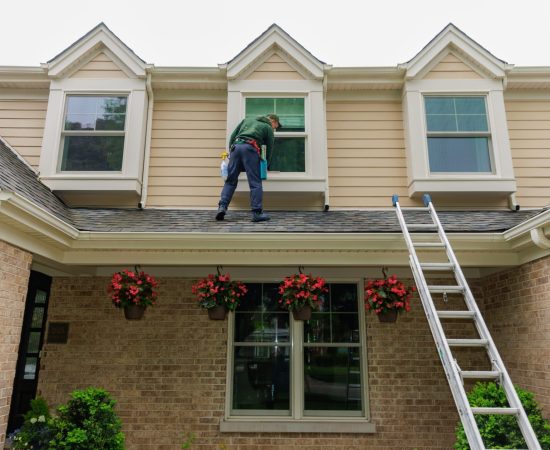 man window cleaning second floor windows by standing on the roof