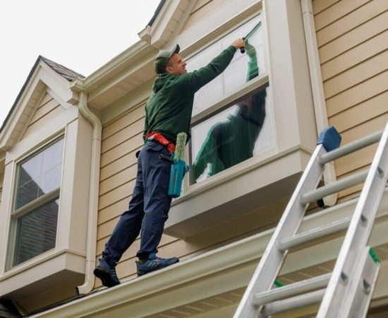 man is washing a window by standing on the roof